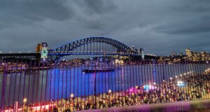 View from the Tarpeian Lawn of evening in Sydney, looking to the Harbour Bridge, and looking over people gathered near the Opera House